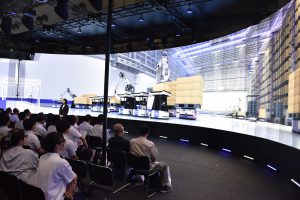 Daifuku presents the logistics environment of the near future on a giant monitor. Visitors view it with 3D glasses.