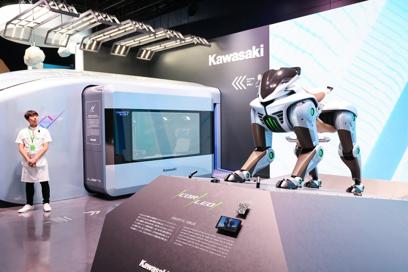 KHI's booth attracts attention with the CORLEO robot. The box-shaped structure in the background is the ALICE Cabin. 