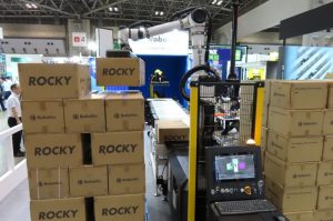 Depalletizing robot connected to collaborative palletizing robot via extendable conveyor 